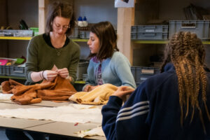 Atelier textile : une animatrice et des participantes travaillant des matières orange autour d'une table