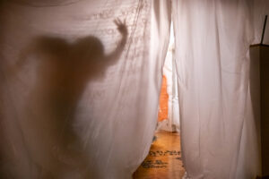 Silhouette d'une personne en mouvement derrière un rideau blanc translucide